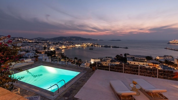 Une piscine sur le toit offrant une vue sur une ville côtière au crépuscule.