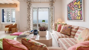 Un salon avec un canapé, une table basse et une vue sur l’extérieur, visible à travers une porte vitrée.