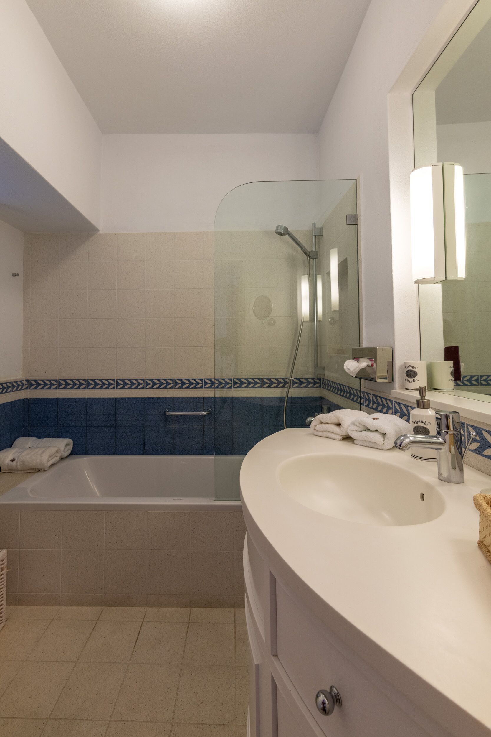 A bathroom with a bathtub, a shower, a sink, and a mirror.