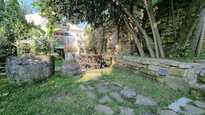 Un mur de pierre, un banc de pierre et un chemin de pierre dans un espace jardin.