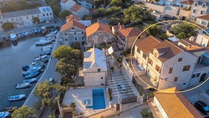 Un pueblo costero con edificios de piedra, un puerto deportivo y una piscina.