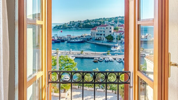 Una ventana abierta con vista a un puerto, barcos y edificios.