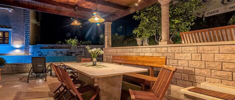 Un patio al aire libre con un muro de piedra, muebles de madera y una piscina.