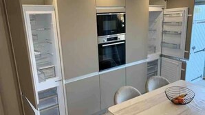 Uma cozinha moderna com eletrodomésticos embutidos, uma mesa de jantar e uma fruteira.