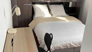 Um quarto com uma cama, uma escrivaninha e uma cadeira.