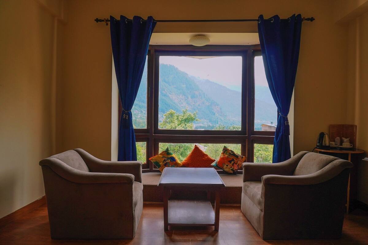 A room with two armchairs, a small table, and a window with curtains.