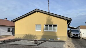 A yellow building with two windows and a garage door. - Vacation apartment in the countryside (Lebach Landsweiler)