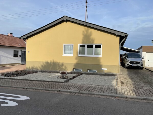 Ein zweistöckiges Wohnhaus mit gelber Fassade, einer Garage und einem gepflasterten Einfahrt.