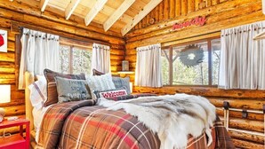 A cozy log cabin bedroom with a plaid bedspread, a welcome pillow, and a fur throw. - Chic, updated log cabin nestled in the pine trees of Sprucewold! (Boothbay Harbor)