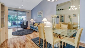 Una sala de estar moderna con una mesa de vidrio, sillas color beige, un sofá y un espejo grande.