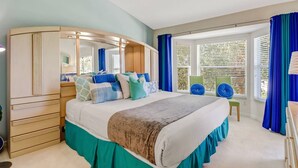 Un dormitorio con una cama grande, un armario, un espejo y una ventana con cortinas.