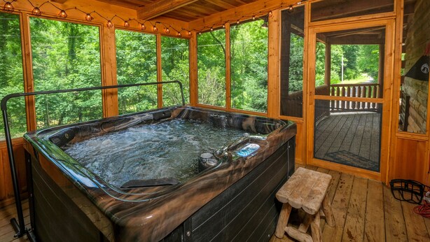 Un bain à remous dans un chalet en bois avec vue sur la forêt.