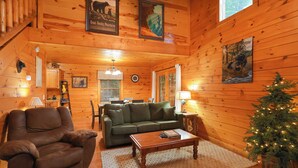 L’intérieur chaleureux d’un chalet avec un canapé, un fauteuil, une table basse en bois et un sapin de Noël.