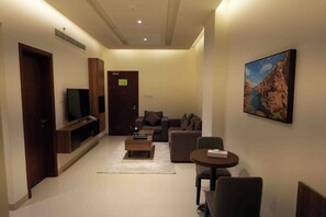 Una sala moderna con una televisión de pantalla plana, un sofá, una mesa de centro y una pequeña mesa de comedor.