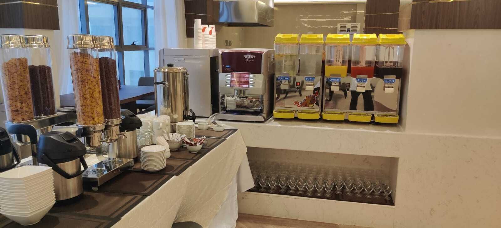 En morgenmadsbar med kaffemaskiner, juiceautomater og en kaffekande.