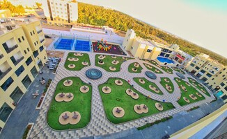 Vista aérea de un patio de hotel con varias zonas de estar, un parque infantil y una piscina.