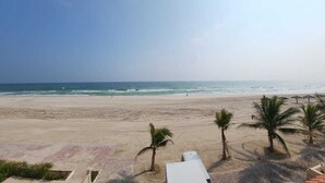 Una playa con cielo despejado, palmeras y vistas al océano.
