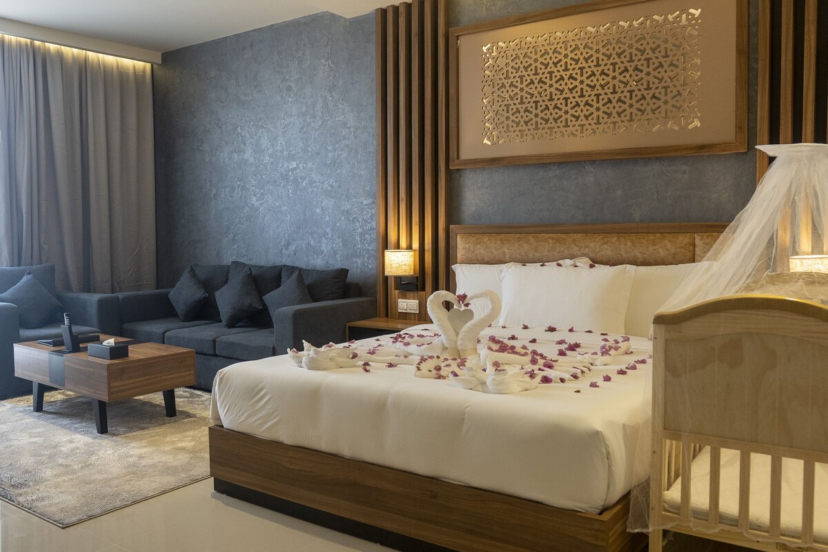Een hotelkamer met een bed, een slaapbank, een nachtkastje, een lamp en een decoratief paneel aan de muur.