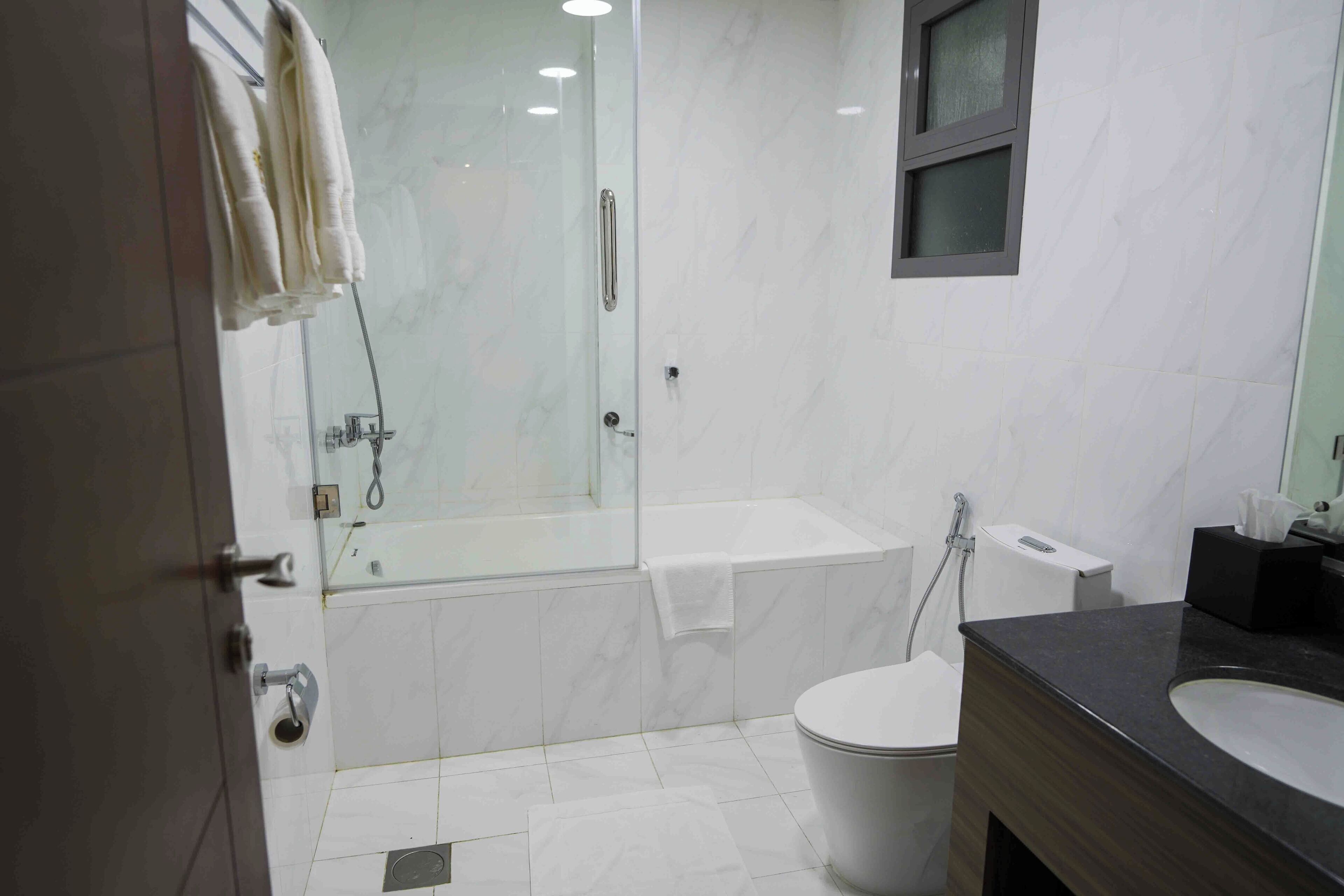 Un baño moderno con ducha de vidrio, bañera, inodoro y tocador con lavamanos.