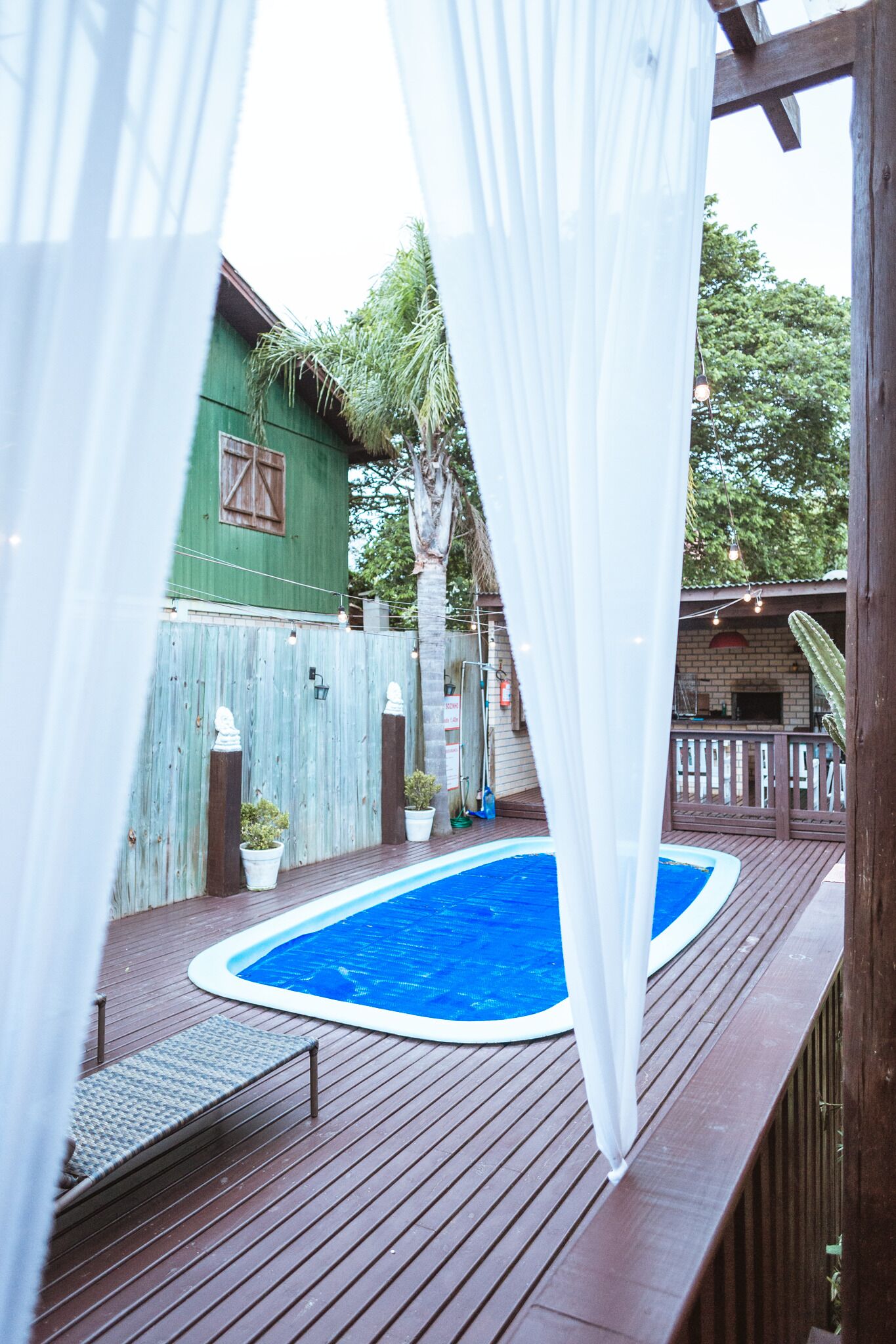 A wooden deck with a swimming pool, surrounded by a wooden fence and potted plants.