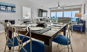 Een eetruimte met een grote tafel voor zes personen, omringd door blauwe fauteuils.