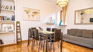 Un soggiorno moderno con zona pranzo, pavimento in legno e divano grigio.