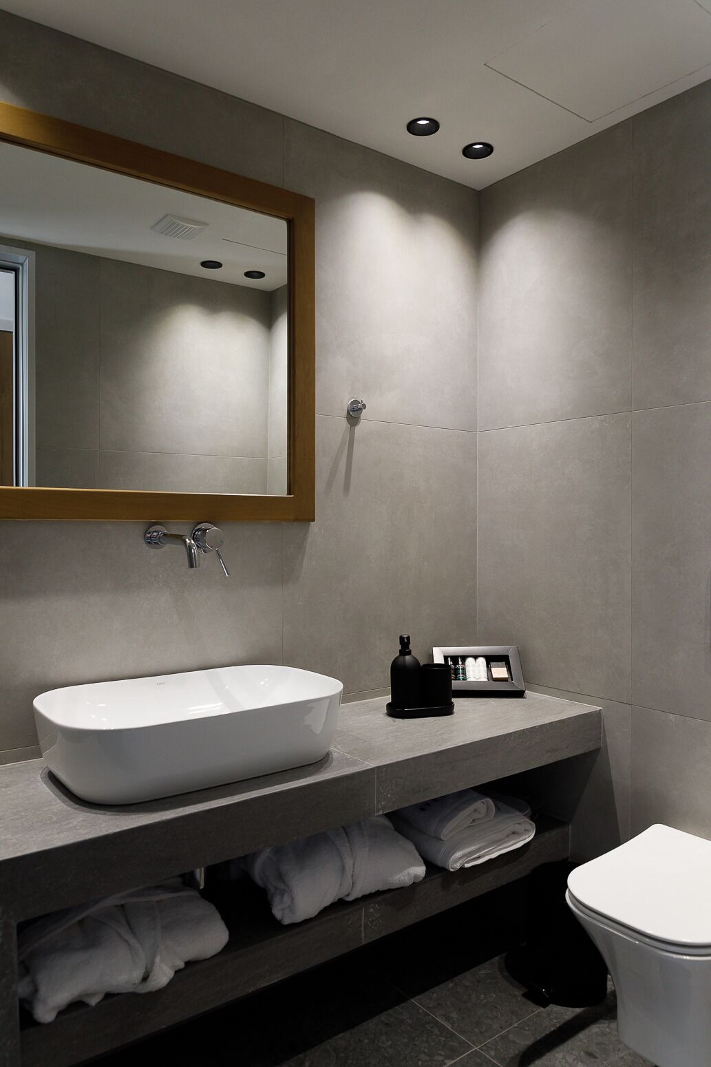 Un baño moderno con un lavamanos grande de color blanco, un espejo y un inodoro.