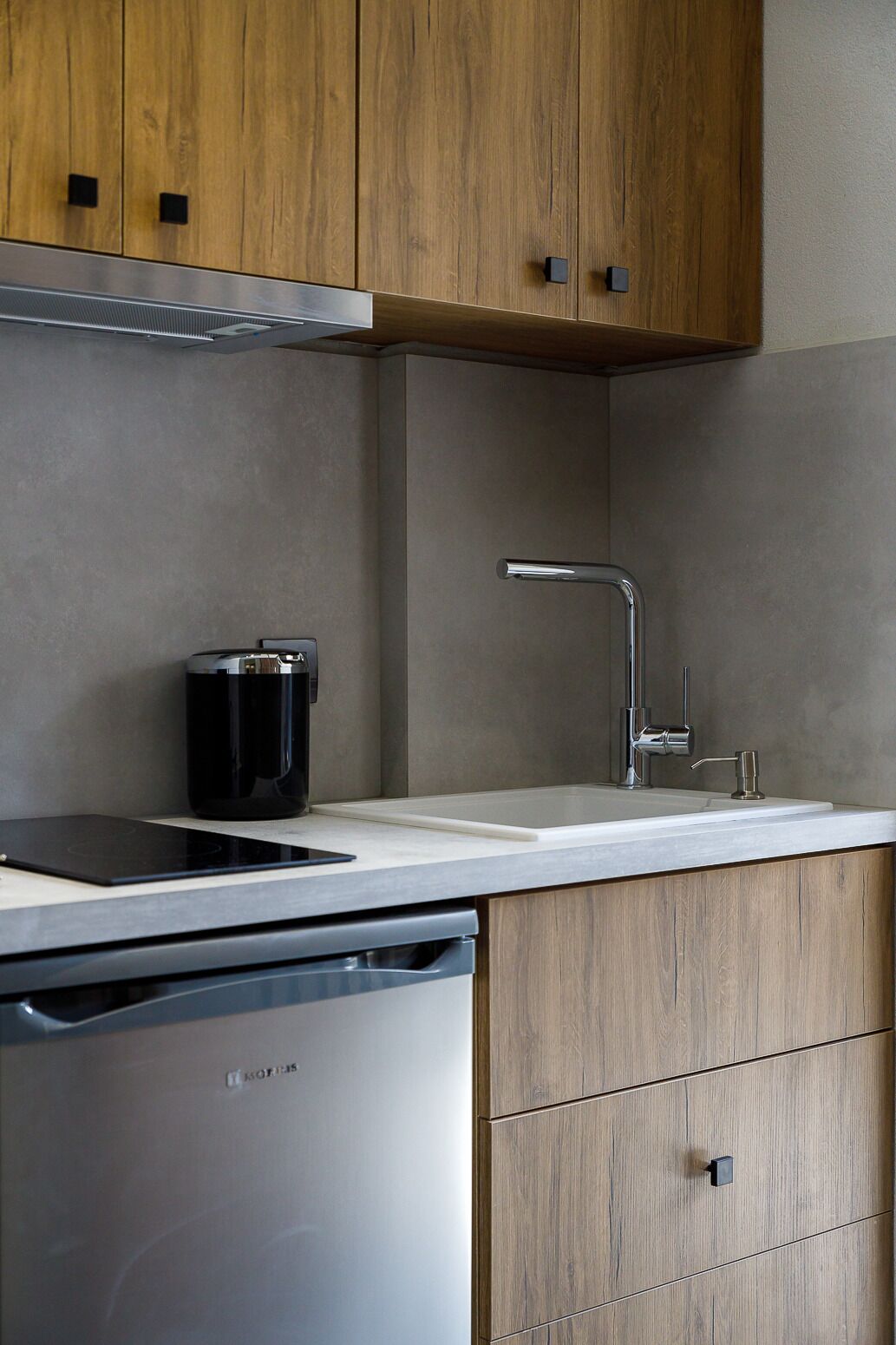 Une cuisine moderne avec des meubles en bois, un lave-vaisselle en acier inoxydable et une machine à café noire.