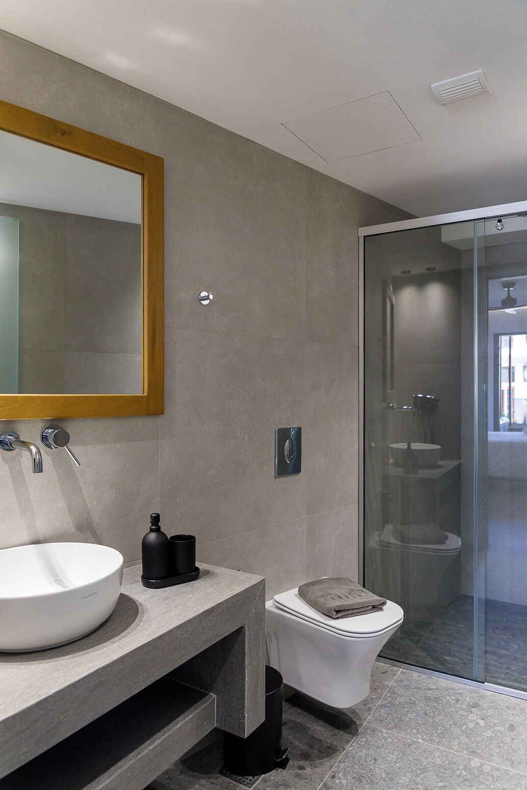 A modern bathroom with a large mirror, a sink, a toilet, and a shower area.