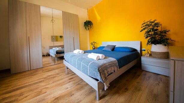 Une chambre à coucher avec un lit, des tables de chevet, une plante suspendue et une armoire.