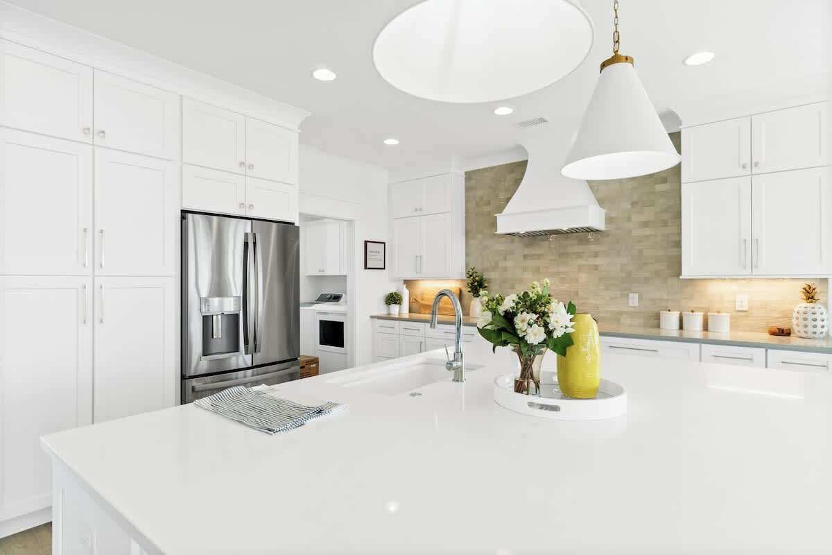 A modern kitchen with white cabinetry, stainless steel appliances, and a central island with a sink.