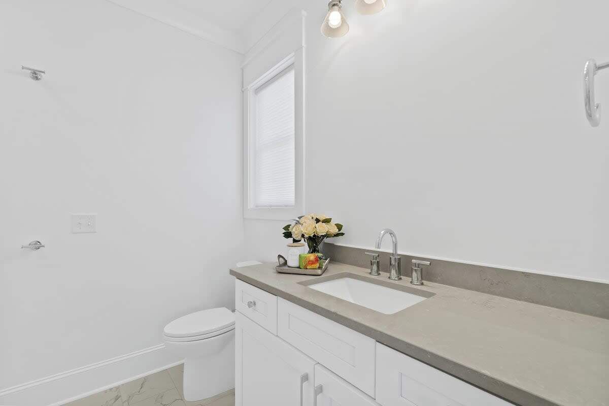 Un baño moderno con inodoro blanco, lavamanos con espejo y zona de ducha.