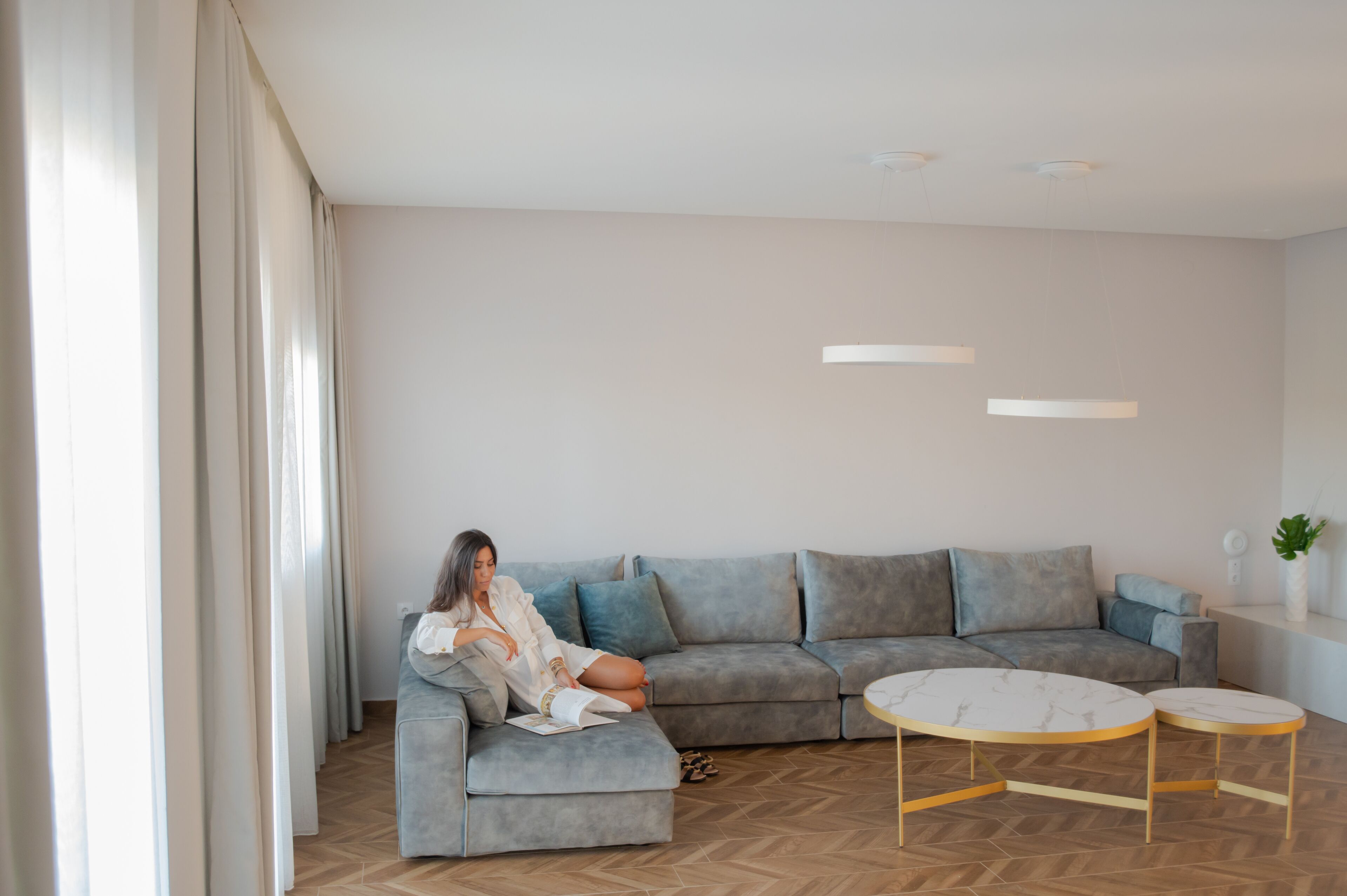 Una sala de estar moderna con un sofá seccional gris, una mesa de centro blanca y una mesita auxiliar con una planta.