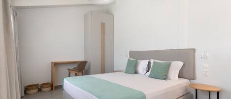 A bedroom with a bed, bedside table, chair, and a desk.