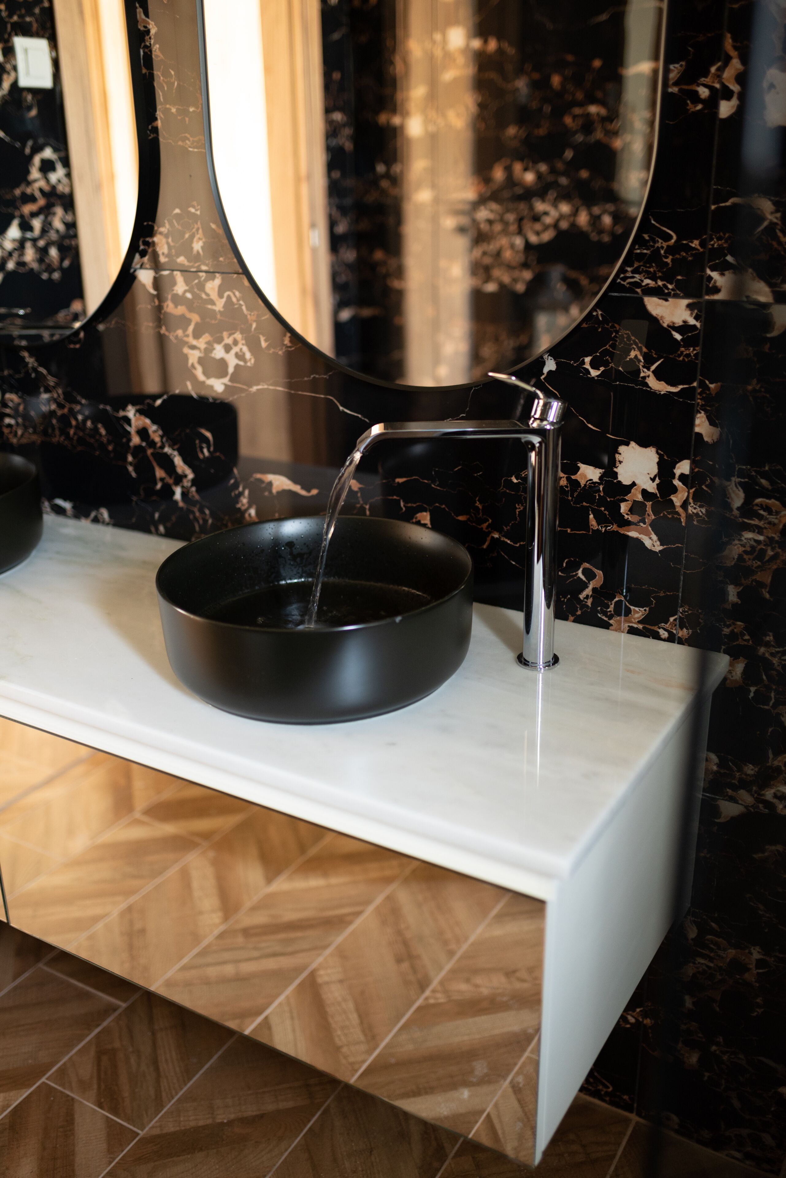 A modern bathroom with a black basin, a chrome faucet, and a mirror above the sink.
