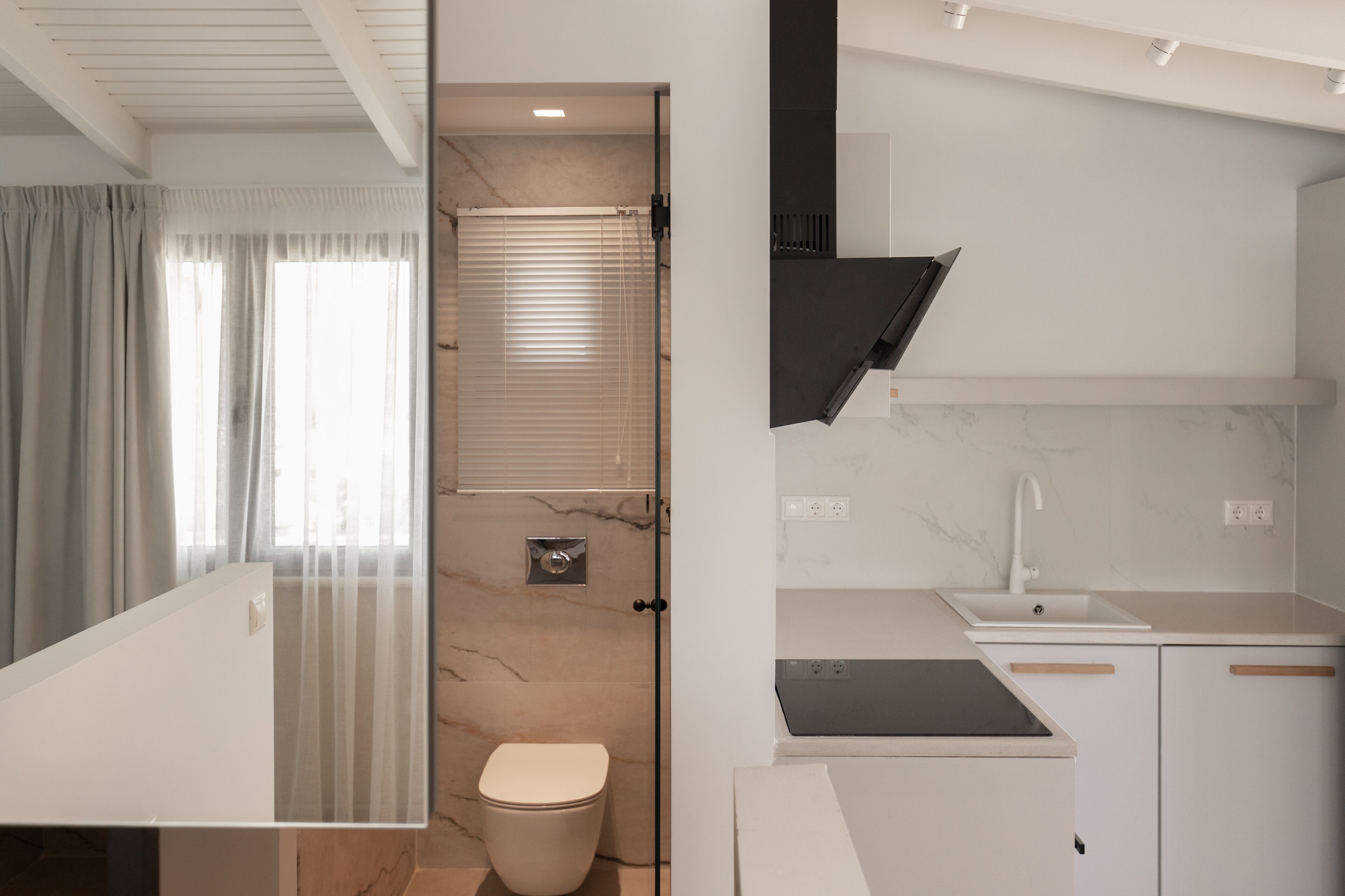 A modern bathroom with a toilet, shower, and a glass partition.