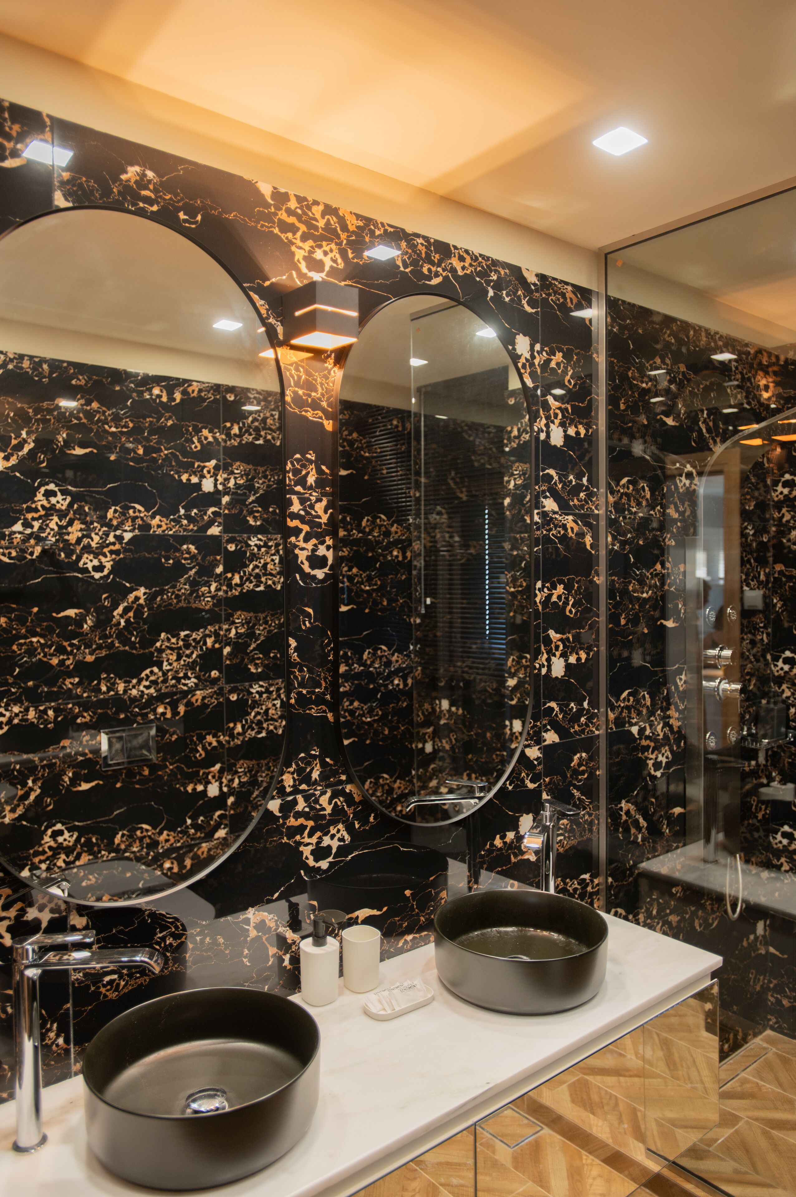 A bathroom with two black sinks, a large mirror, and marble walls.