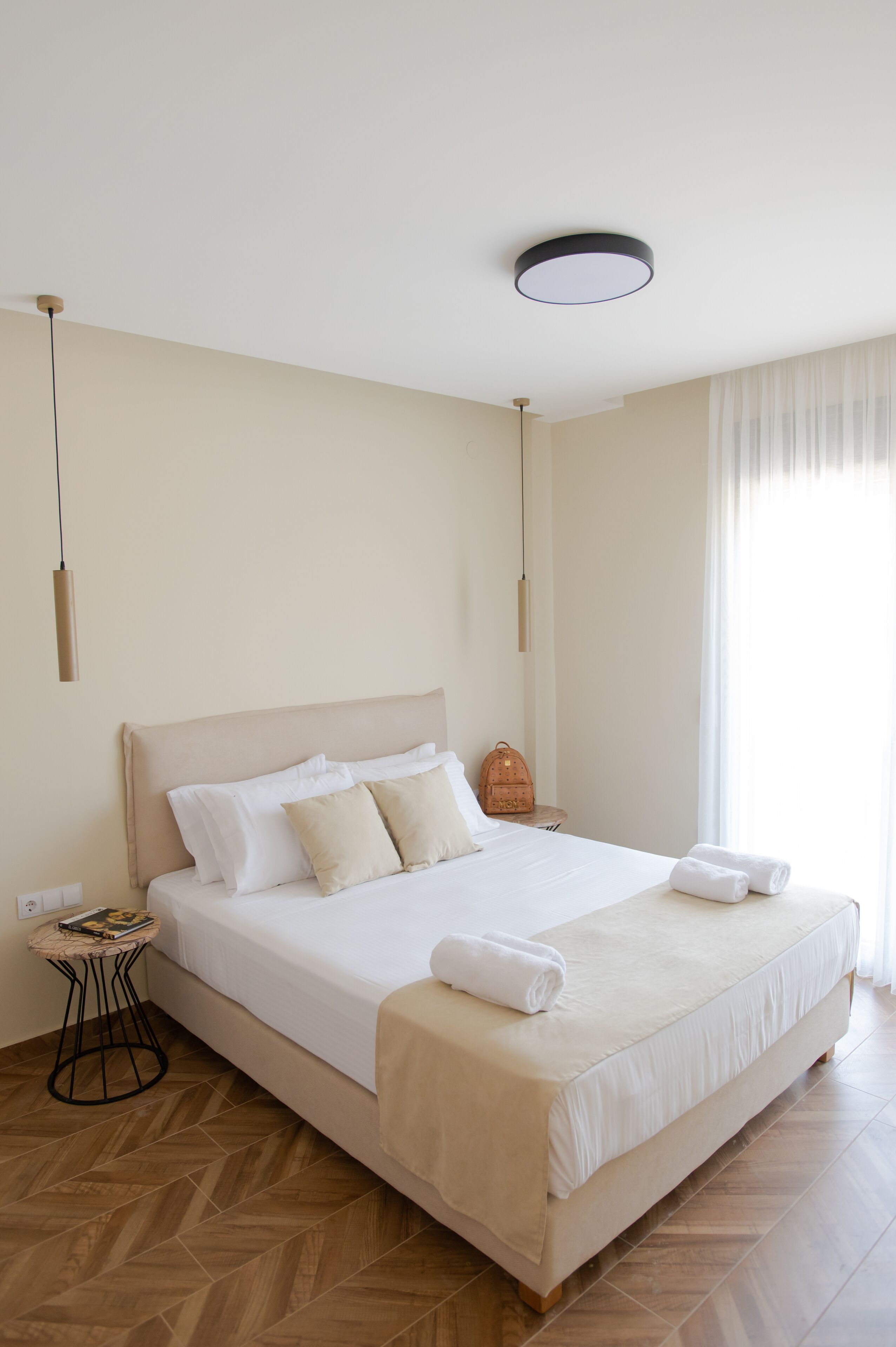 Un grand lit avec une tête de lit, une table de chevet et un luminaire suspendu.