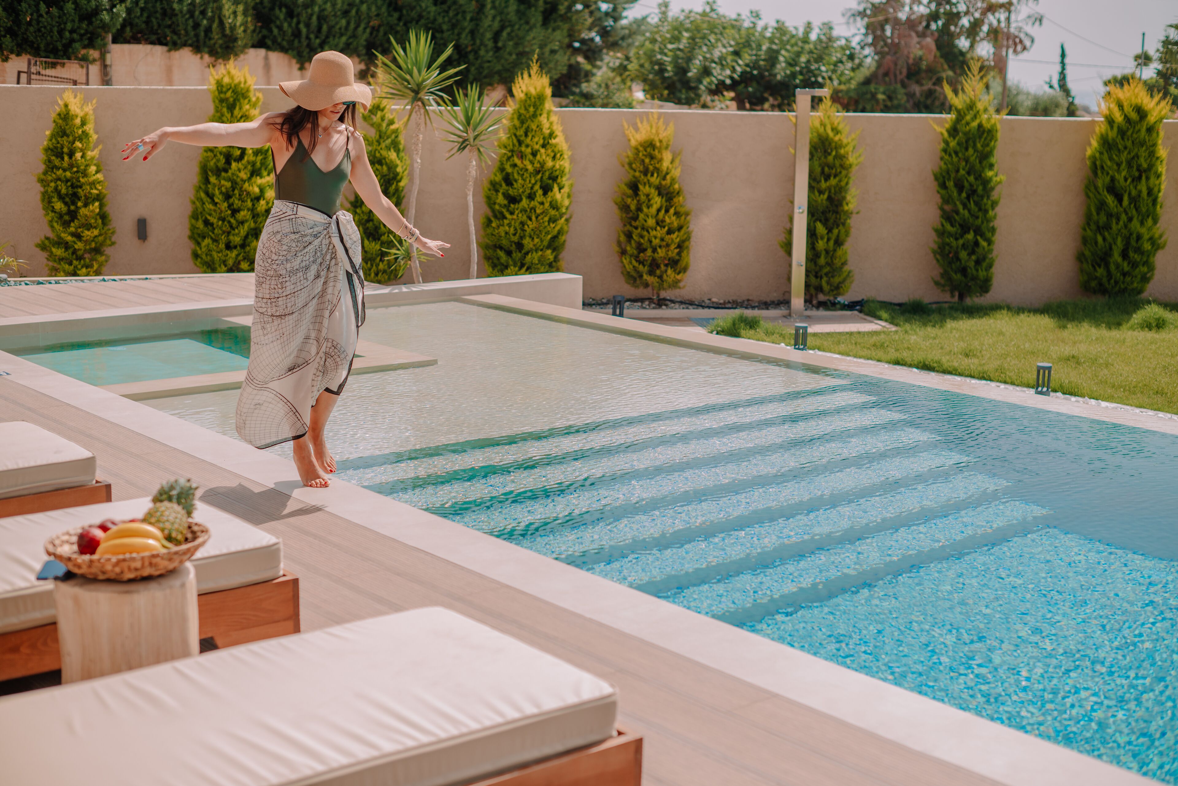 A swimming pool with lounge chairs and a fruit basket.