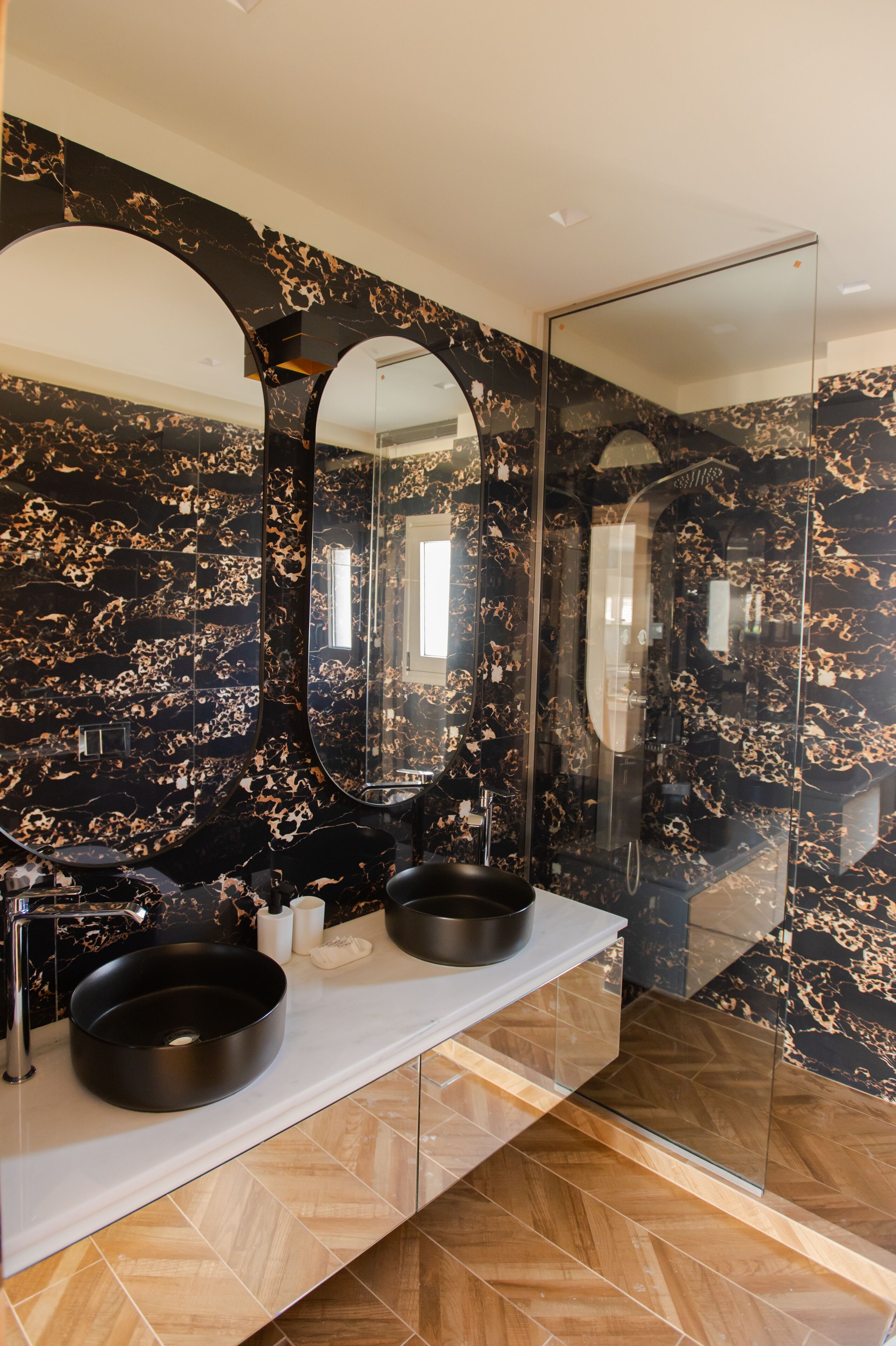 A bathroom with two black sinks, a large mirror, and a glass shower enclosure.