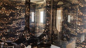 A bathroom with two black sinks, a large mirror, and a glass shower enclosure.