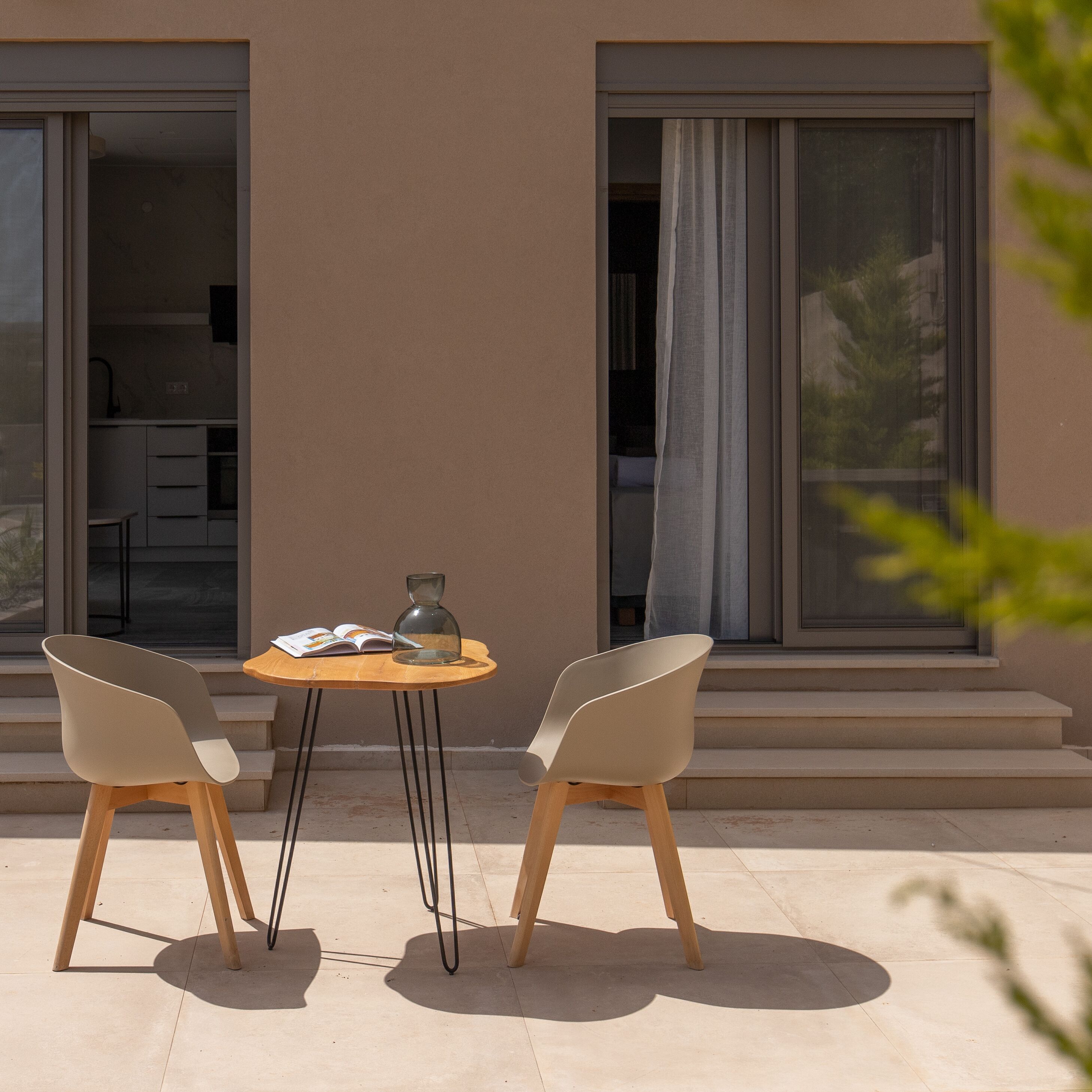 An outdoor seating area with two chairs and a table, a book, and a vase.