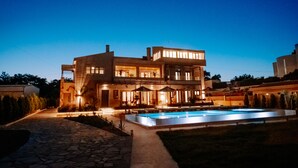 A modern two-story house with a swimming pool, stone pathway, and outdoor seating area. - Marble Luxury Suites (Heraklion)