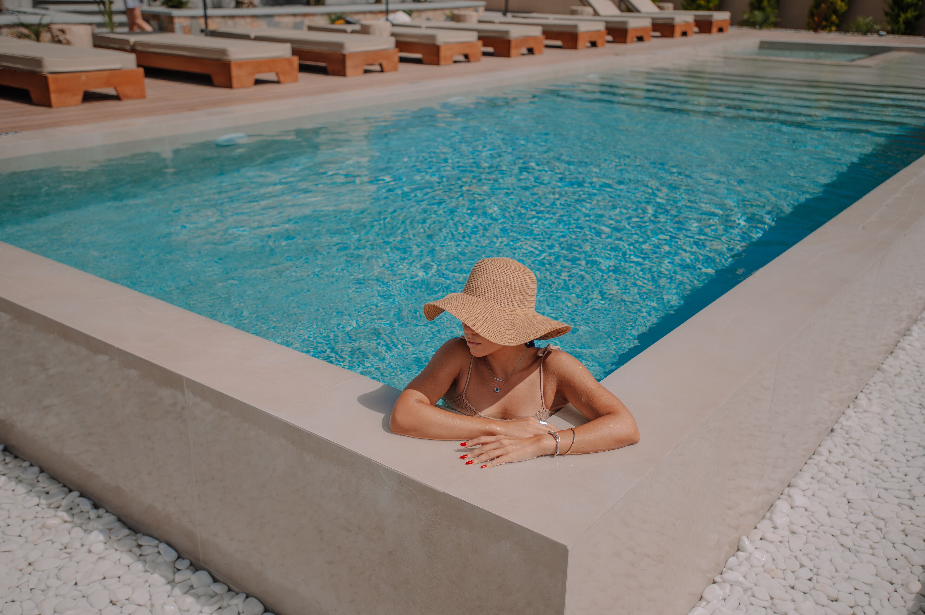 A poolside area with lounge chairs and a person relaxing by the pool.
