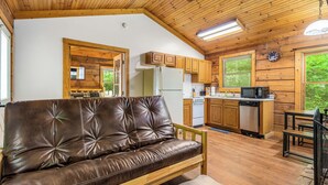 Ein gemütliches Blockhaus-Interieur mit einer Ledersofa, Holzbalkendecke und einer Küchenzeile.