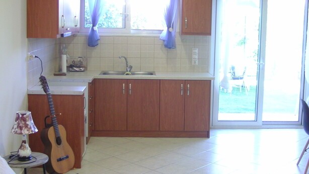 A kitchen with wooden cabinets, a sink, and a guitar. - Remarkable 1-bed Apartment in (Chalcis)