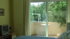 A bedroom with a bed, a television on a wooden nightstand, and a balcony with a table and chairs. - Remarkable 1-bed Apartment in (Chalcis)