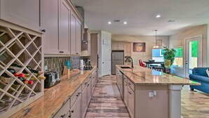 Una cocina moderna con encimeras de mármol, un botellero y una zona de comedor con un sofá azul.