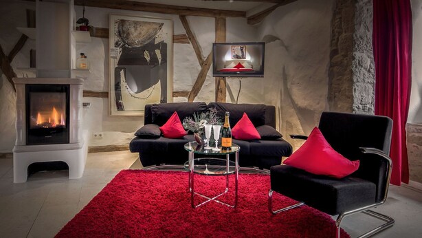 A cozy living room with a fireplace, a sofa set, and a red carpet. - Cozy Studio Suite in Old City (Rothenburg ob der Tauber)