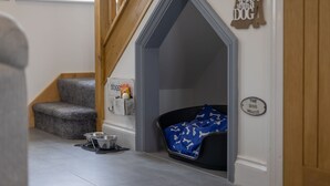 A dog house with a sign reading "The Dog House" and a dog bowl on the floor. - Hawthorn Cottage (Tenby)